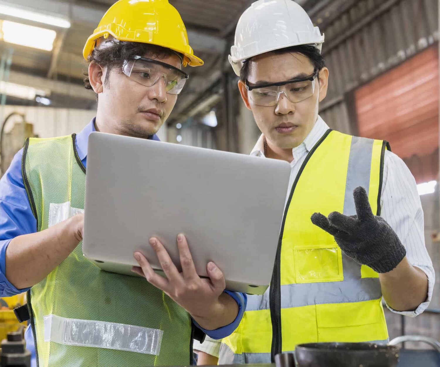 Two professionals discuss recent product education training they received while reviewing content on the laptop while at the job site.