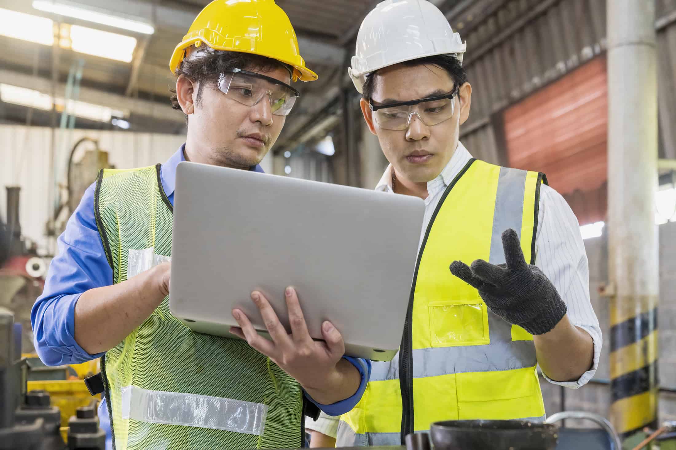 Two professionals discuss recent product education training they received while reviewing content on the laptop while at the job site.